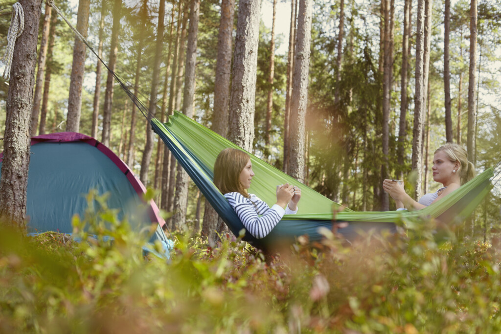 Kompisar vilar i hängmatta i naturen