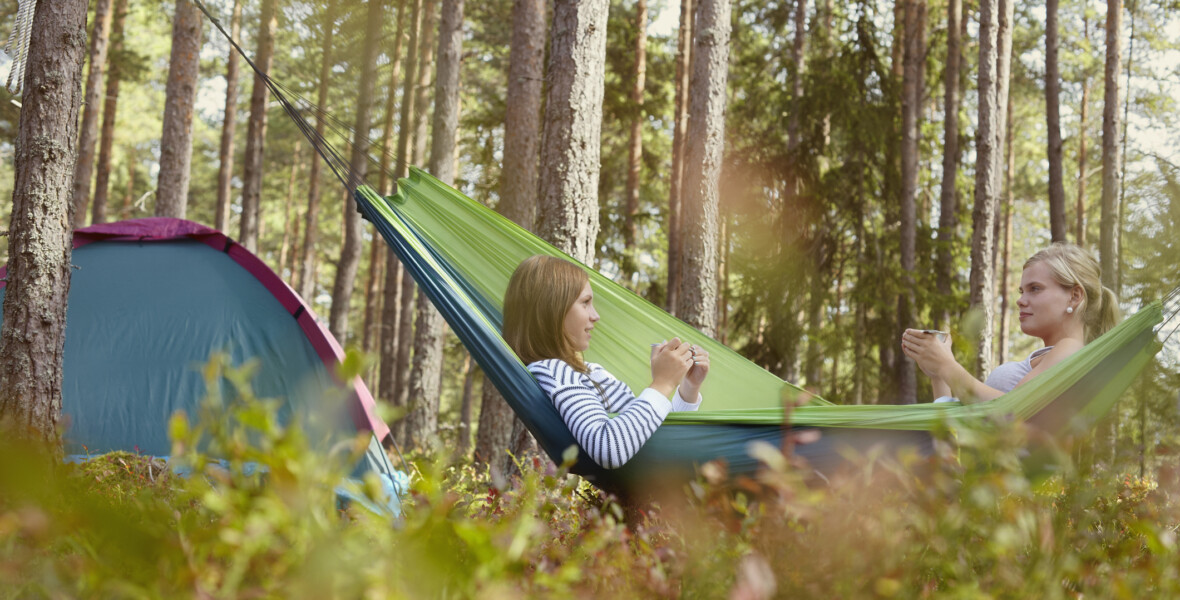 Kompisar vilar i hängmatta i naturen