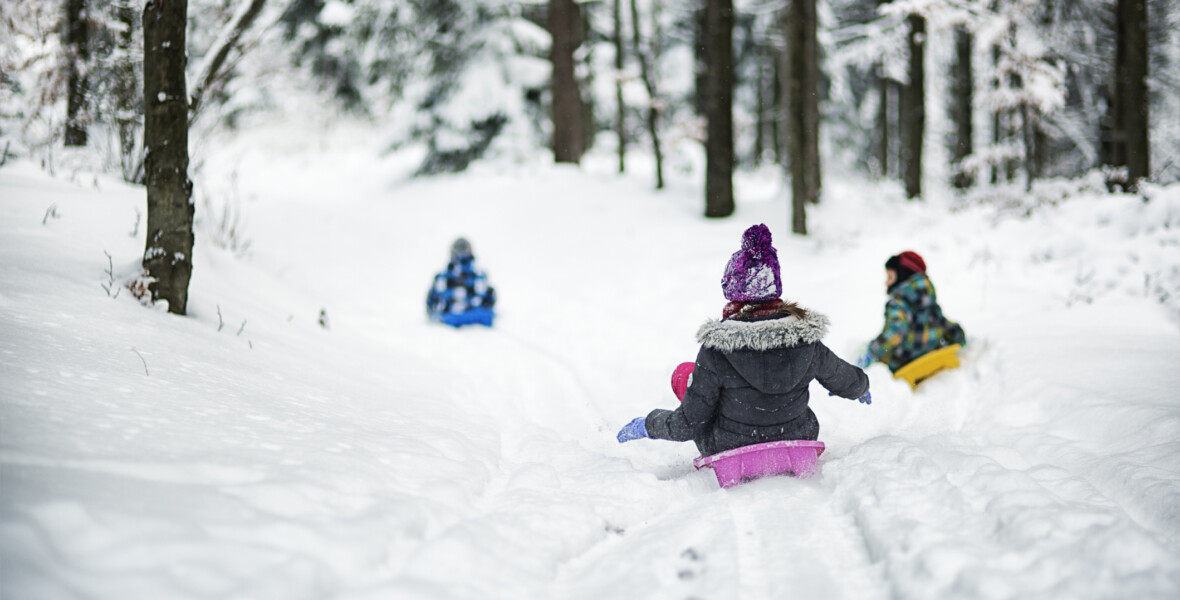 Tre barn åker pulka i snön