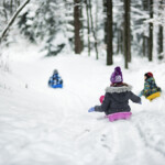 Tre barn åker pulka i snön