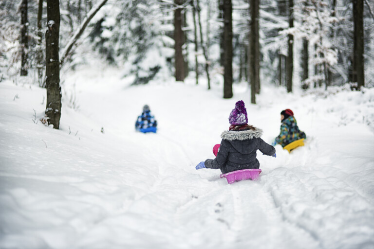 Tre barn åker pulka i snön