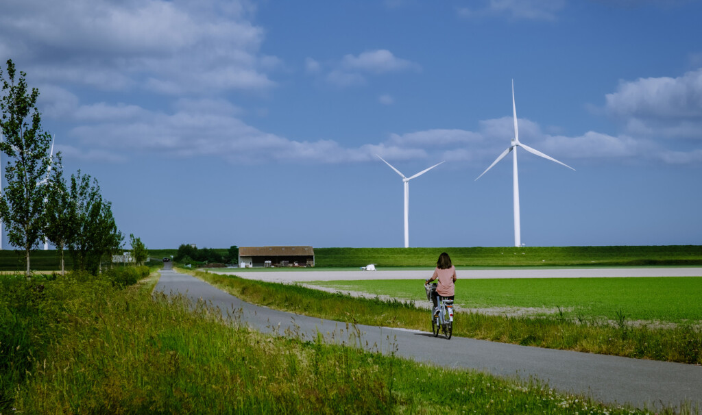 Cyklist på landsväg med vindkraft i bakgrunden