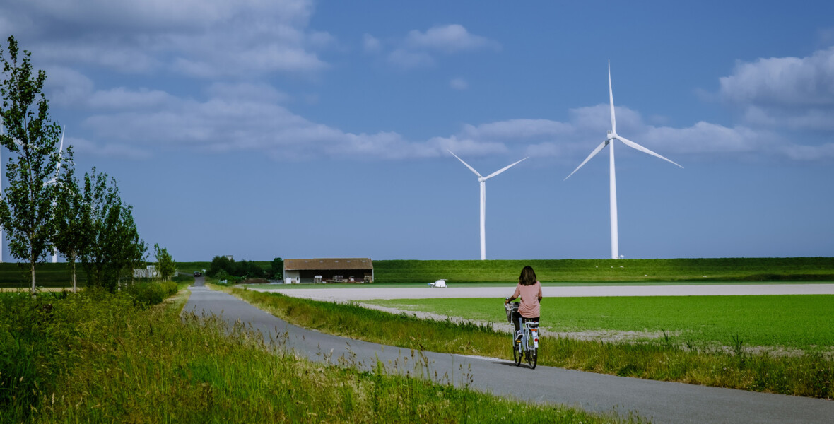 Cyklist på landsväg med vindkraft i bakgrunden