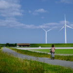 Cyklist på landsväg med vindkraft i bakgrunden