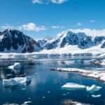 Berg täckta av snö och is vid vatten.