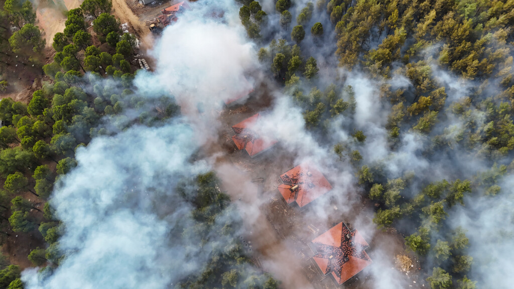 Rök från en skogsbrand sprider sig över bostadshus